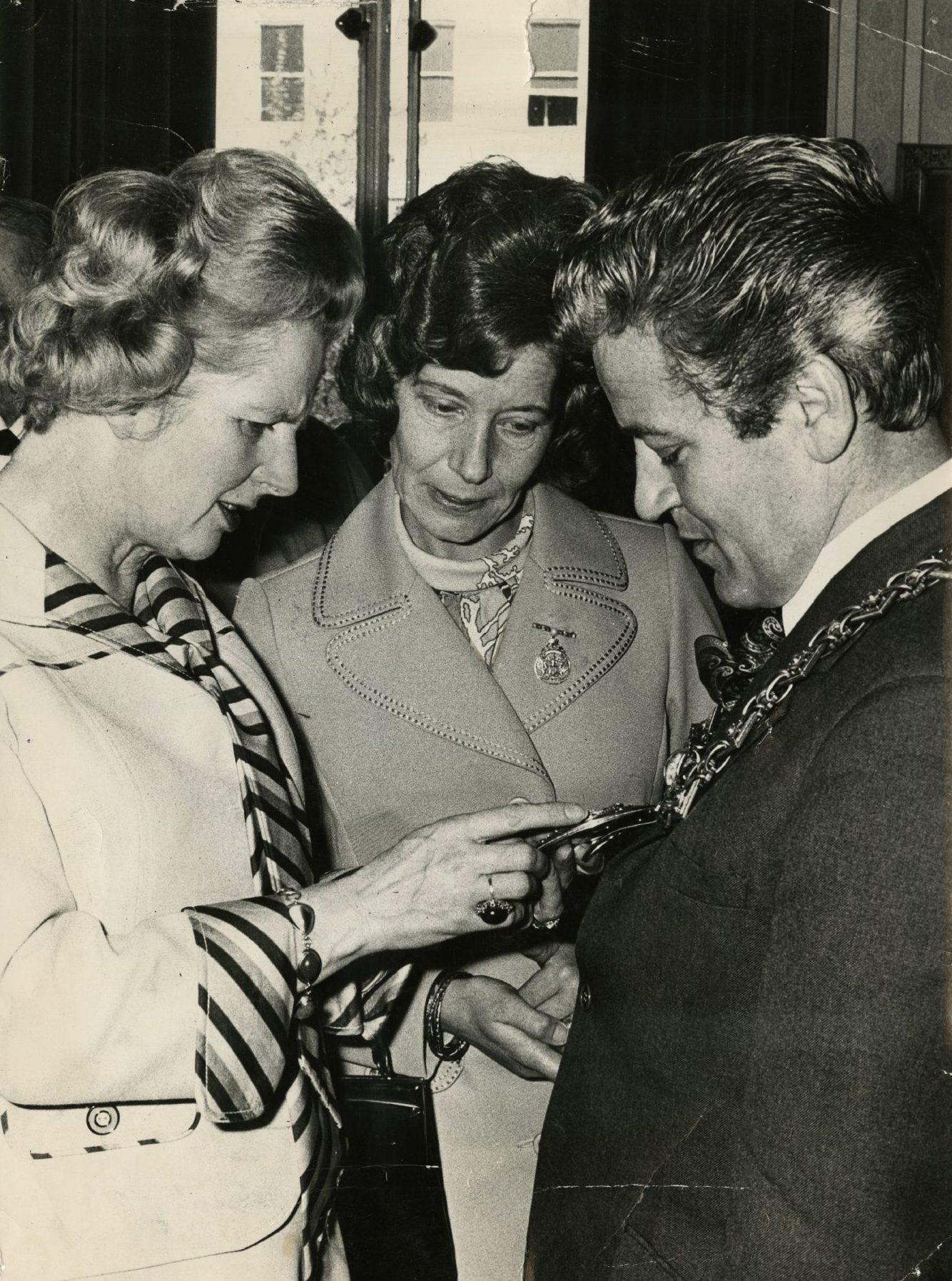 a woman looks on as Margaret Thatcher inspects Lord Provost Charles Farquhar's chain of office