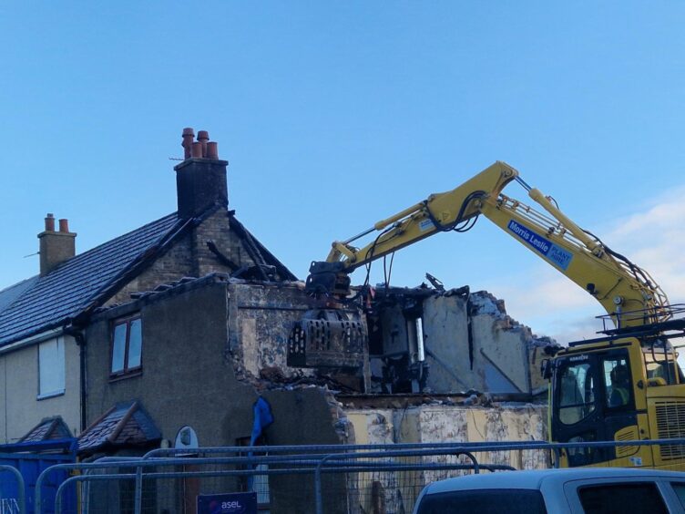 An excavator is removing rubble from the homes. 