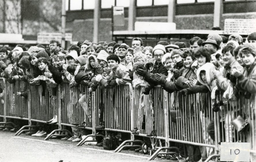 Spectators at High Street brave the rain to watch the runners. Image: DC Thomson.