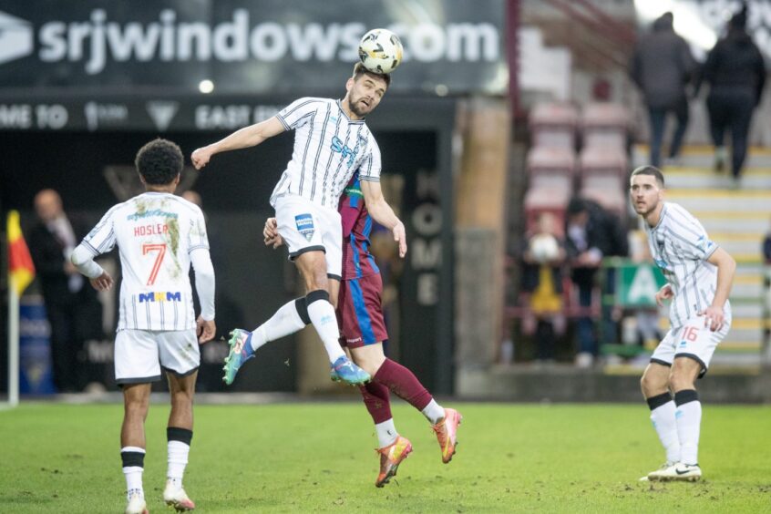 Aaron Comrie rises high to win a header for the Pars.