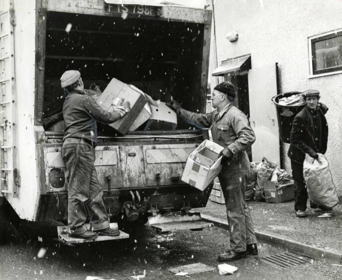 Jim Anderson, George Neil and Tom Mullen throwing rubbish in the back of a bin lorry