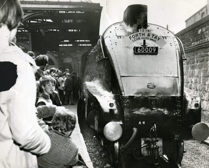 The engine pulls in to Tay Bridge Station, as a crowd lines the platform