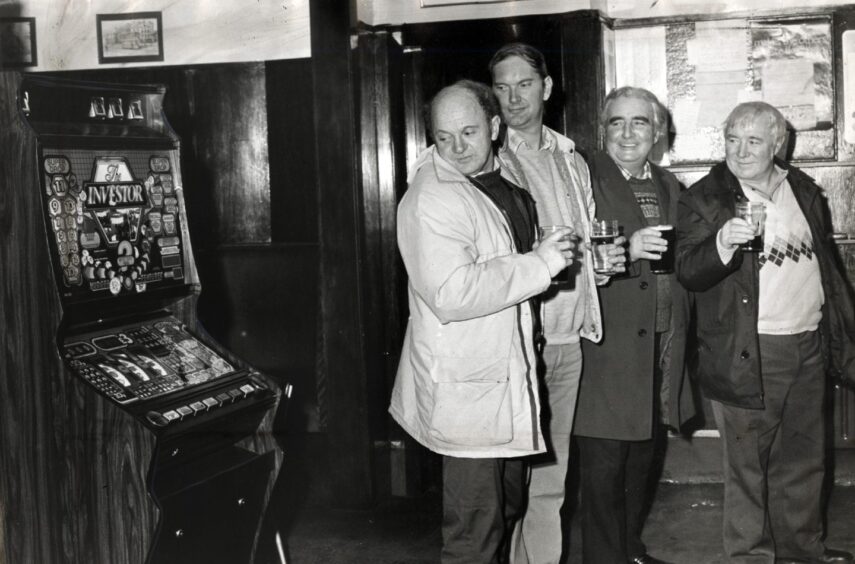 four men holding pints look sideways at the bandit in Sandy's bar