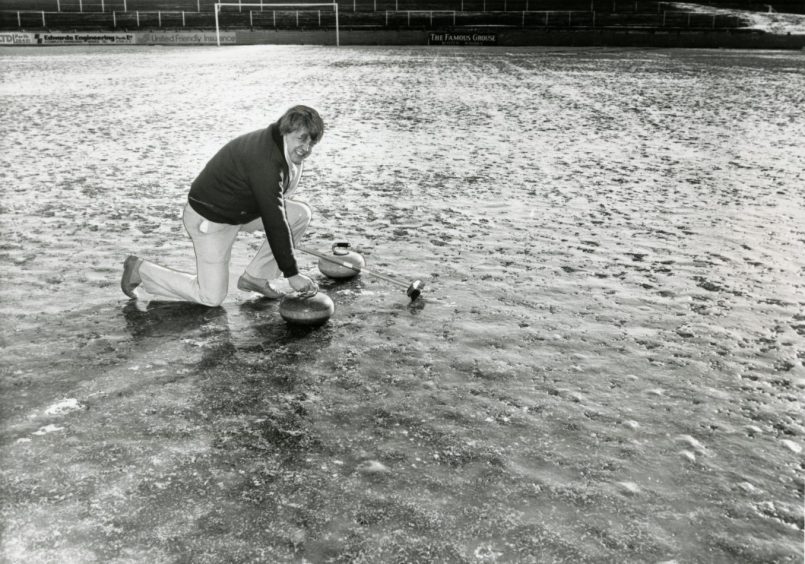 St Johnstone manager Alex Rennie with two curling stones on the Muirton Park pitch. 