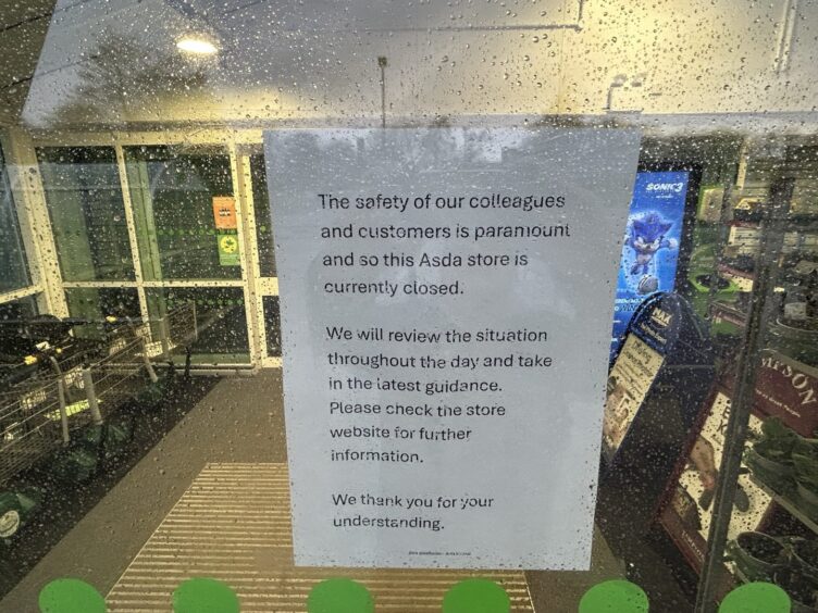 A sign posted inside a glass door indicating the closure at Asda Halbeath in Dunfermline. 