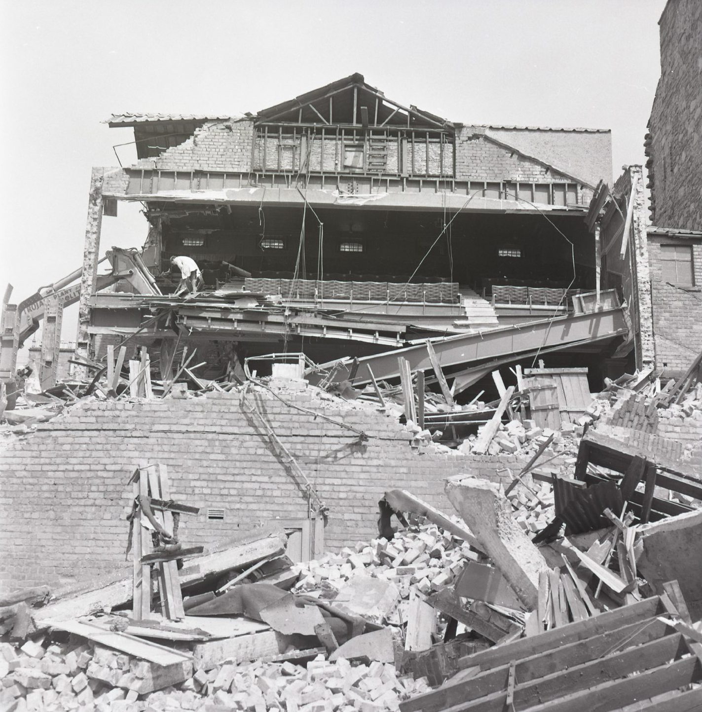 A workman on the balcony during the demolition of the Royalty Kinema, with the inside of the building exposed and the foreground dominated by piles of rubble