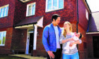 young family with baby standing outside their home