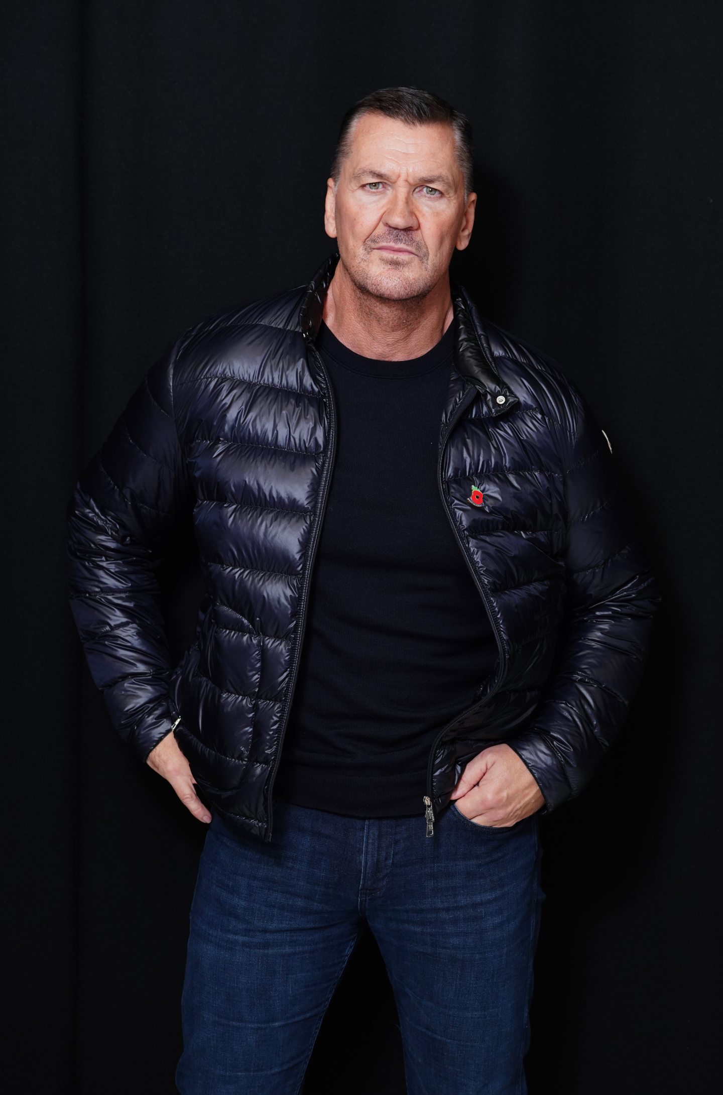 Rise of the Footsoldier actor Craig Fairbrass in jeans and a puffer jacket looks right at the camera for a press shot