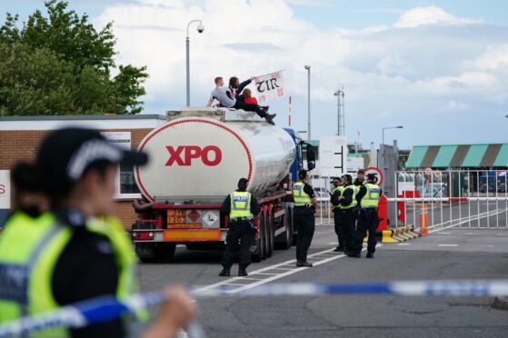 Police officers watch as protesters from This Is Rigged sit on top of an oil tanker at the Ineos refinery in Grangemouth, Fife in Scotland. Picture date: Wednesday July 19, 2023. Image: PA