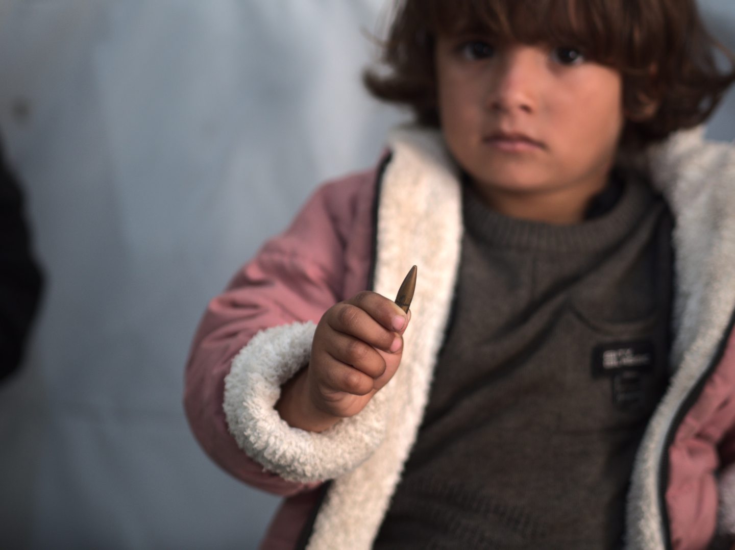 Three-year-old Palestinian girl, Razan, holding the bullet removed from her neck.