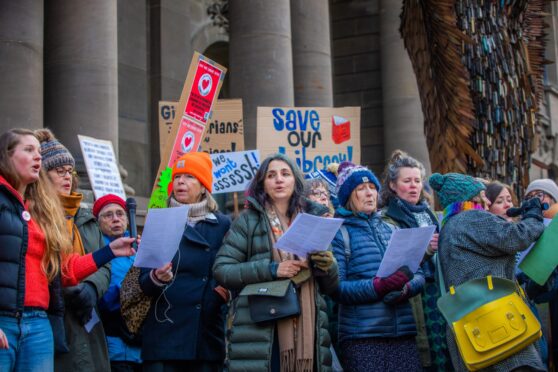 Group of people with 'save our library' placards outside Perth Museum