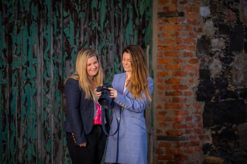 Perthshire wedding photographer sisters Eilidh Robertson and Laura Hay look at their camera together.