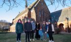 Seven members from the Craigie Community Group stand outside the church.