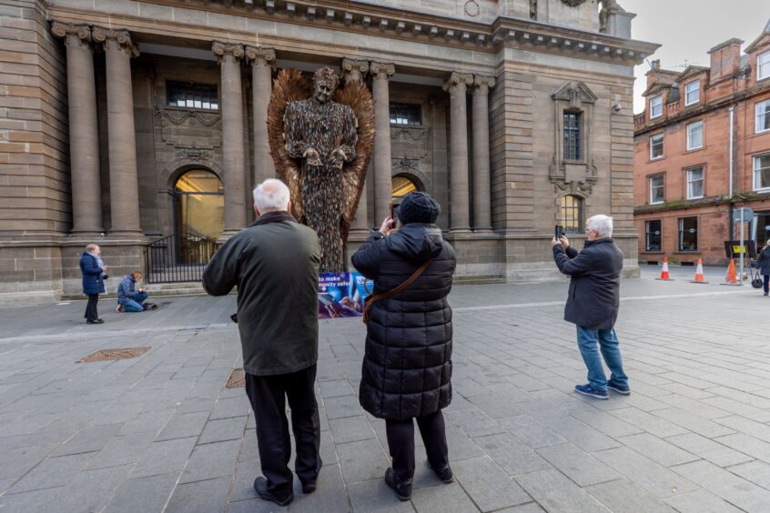 People taking photos of Knife Angel statue outside Perth Museum.