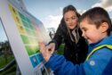 Woman and small boy pointing at symbols on communication board in Methven Park