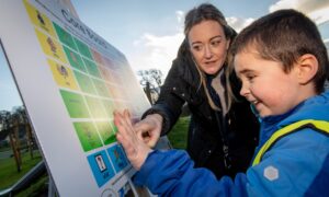 Woman and small boy pointing at symbols on communication board in Methven Park