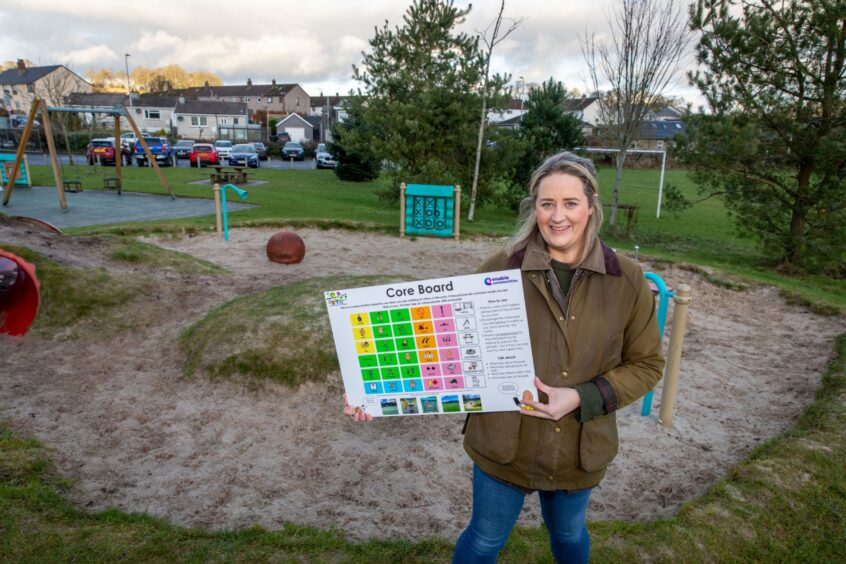 Charlotte Dawson holding one of the communication boards next to play area