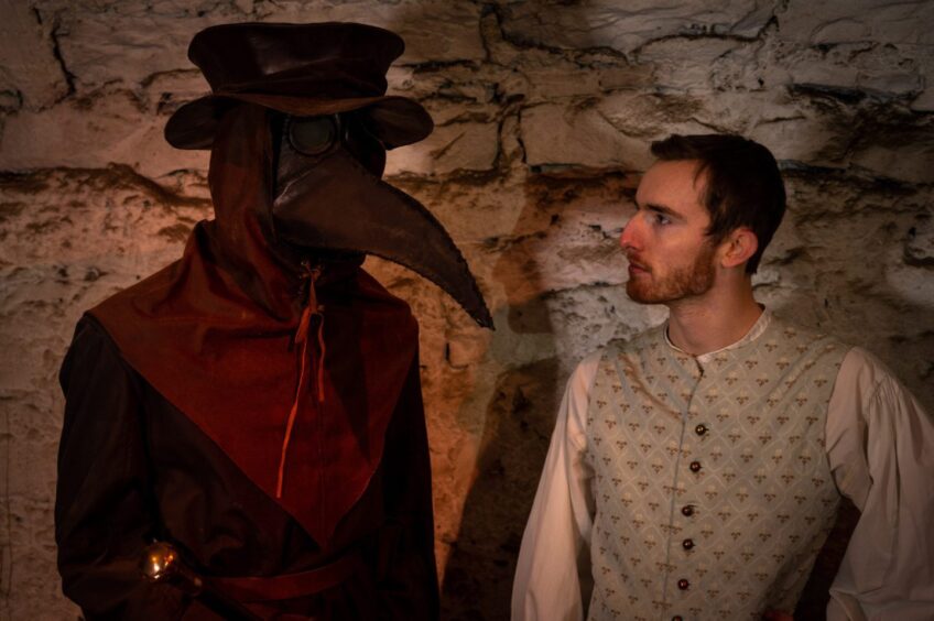 two guides, one dressed as the plague doctor, whose costume makes him look he has a large beak