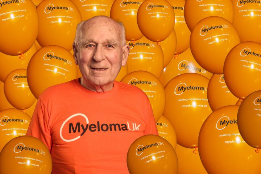 Hugh Henderson in orange Myeloma UK T shirt, surrounded by orange Myeloma UK balloons.