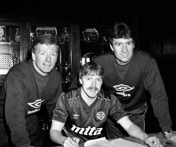 MacKay is flanked by manager Alex MacDonald and assistant Sandy Jardine as he signs for Hearts. 