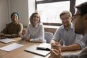 Diverse team of happy colleagues having fun at meeting table, talking, discussing team success, brainstorming on creative ideas, work tasks, planning strategy, laughing, enjoying cooperation