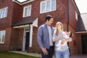 young family with baby outside a new house