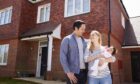 young family with baby outside a new house