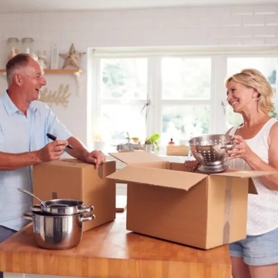 couple takes out kitchen tools from boxes as they are moving house in UK