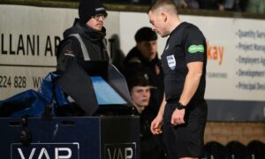 Referee John Beaton consults the VAR monitor at Tannadice. Image: SNS