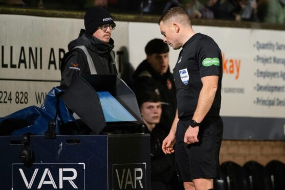 Referee John Beaton consults the VAR monitor at Tannadice. Image: SNS