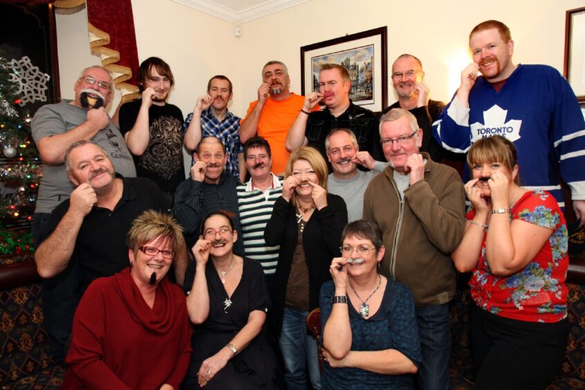 pub regulars pose for a picture with fake moustaches during a Movember charity drive in 2011 