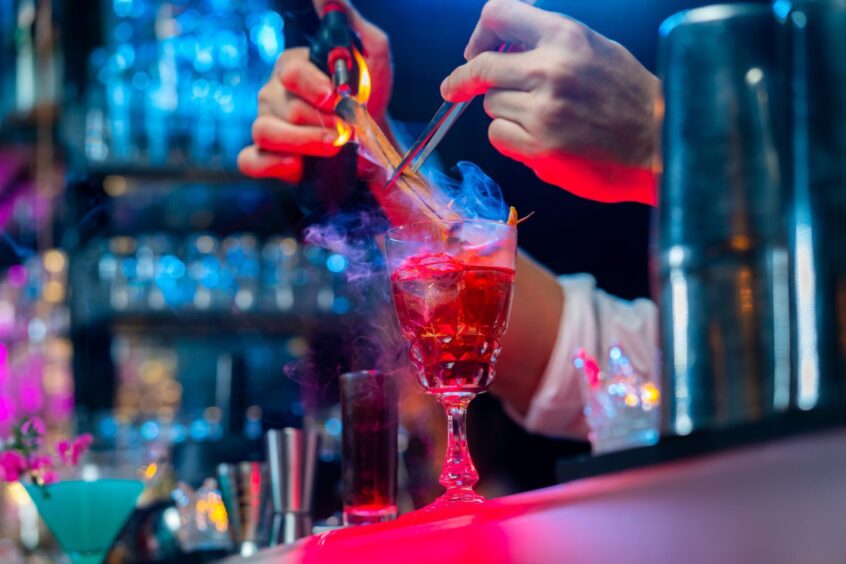 close up of two hands creating a cocktail