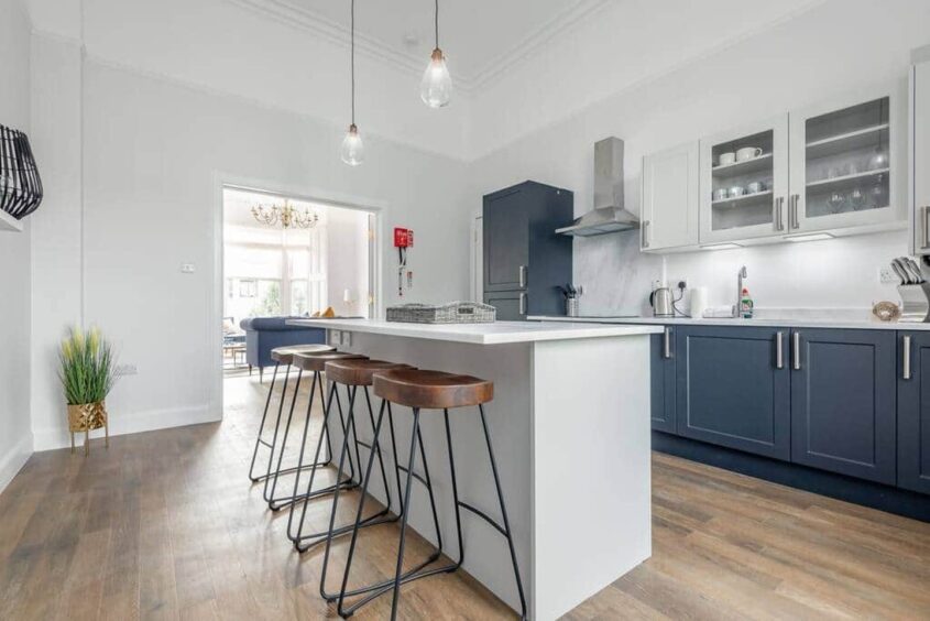 modern kitchen with white and blue cabinets as well as a spacious island with bar stools for an eat-in area 