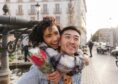 woman holding a bouquet of red roses embraces her boyfriend during a stroll in the city for Valentine's Day 2025