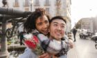 woman holding a bouquet of red roses embraces her boyfriend during a stroll in the city for Valentine's Day 2025