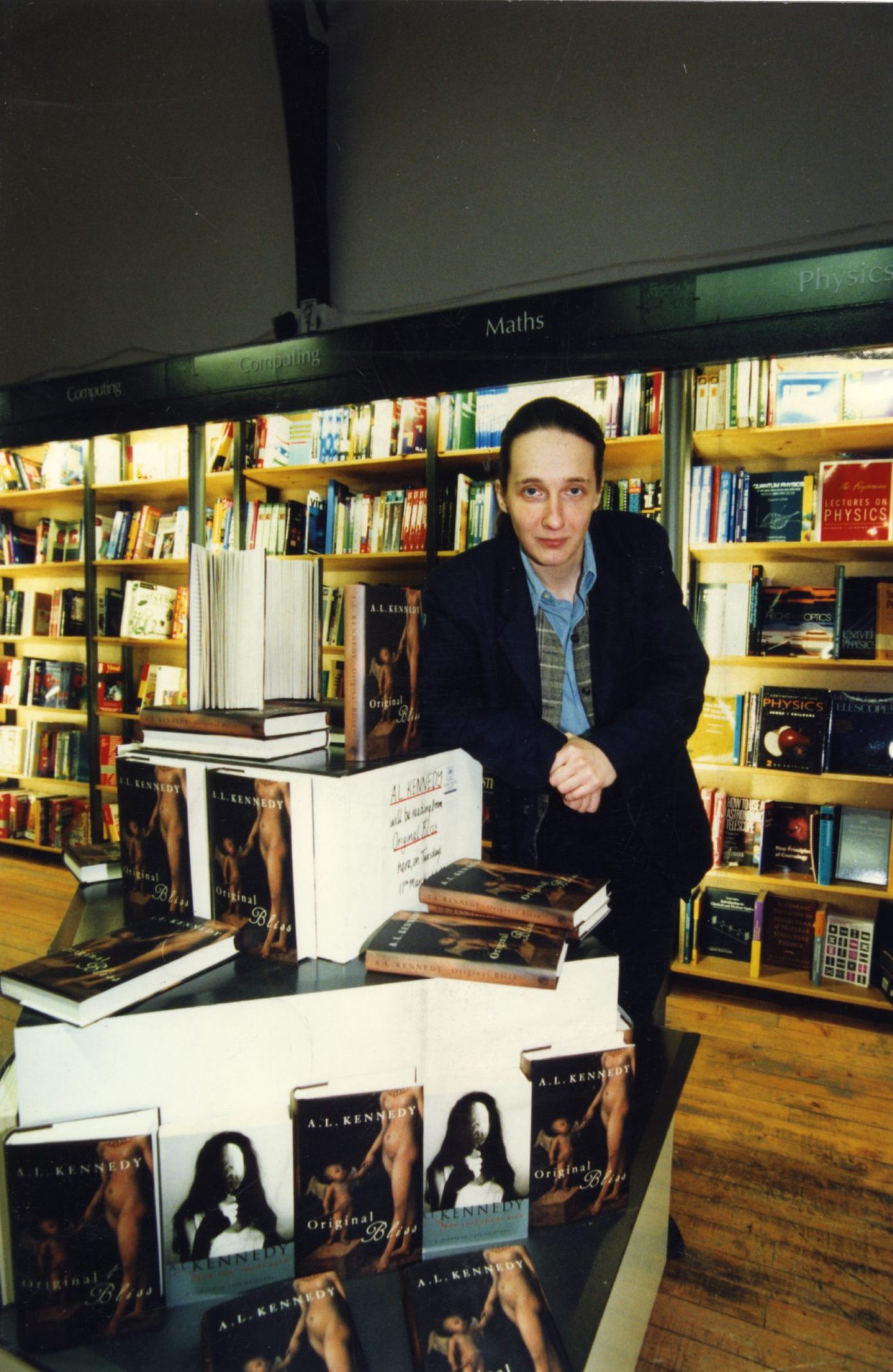 Dundee-born author A.L. Kennedy beside a pile of her books in a book shop