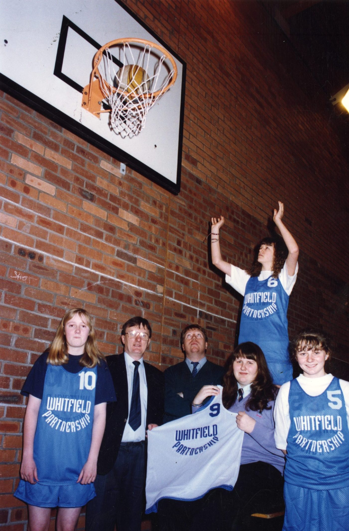 Whitfield High School pupils posing for the camera, while one player shoots a lay up