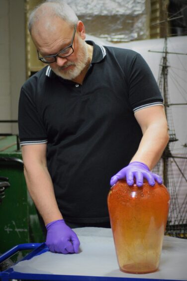 Man holding orange vase