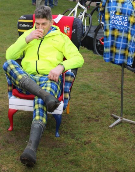 Rob Wainwright, legs crossed, drinking coffee in chair upholstered with rugby shirts