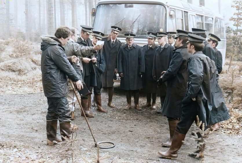 Police standing beside a bus as they prepare to search Templeton Woods in February 1980.