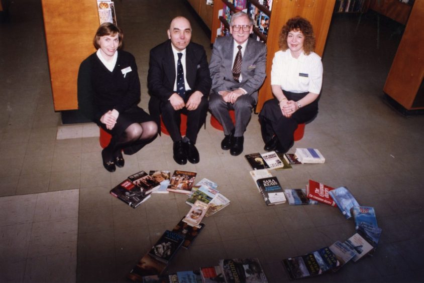 Library staff with books laid out to make the shape of the number 25 in 1994.