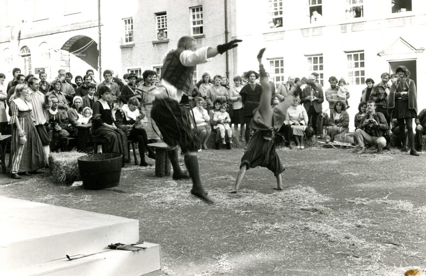 a crowd looks on as acrobats perform in the street at the Stirling Festival in October 1984.