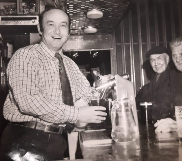 Customers look on as Jeff pours a drink behind the bar at The Three Barrels in Dundee