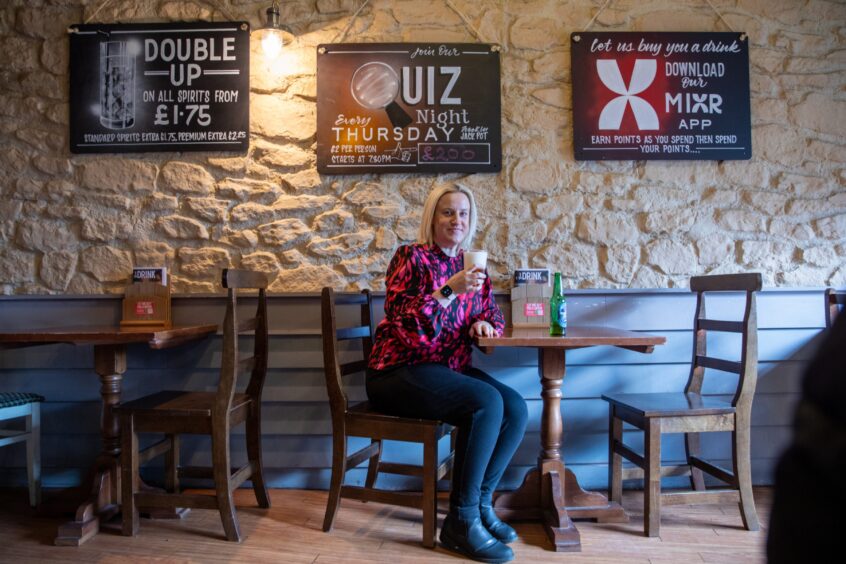 Debbie raises her glass while sitting at a table in the East Port Bar.