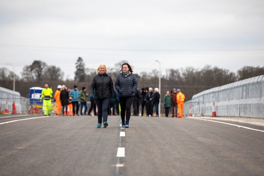 Morag Ritchie and Val Riddell walking across Destiny Bridge with group of people behind them