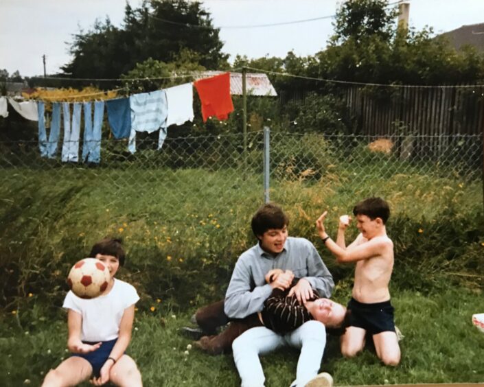 Group of four young people playing on grass in back garden in Malvina Place, Muirton, Perth.