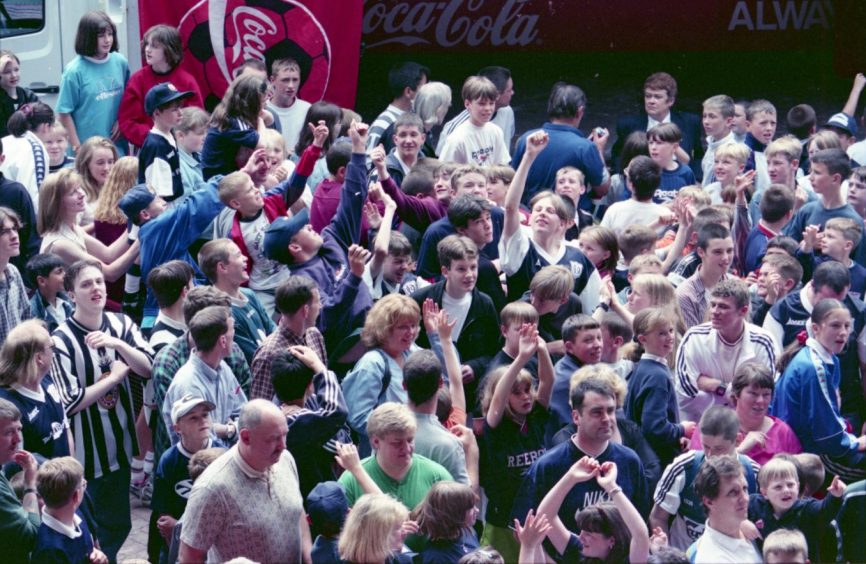 a crowd of Dundee fans on the pitch