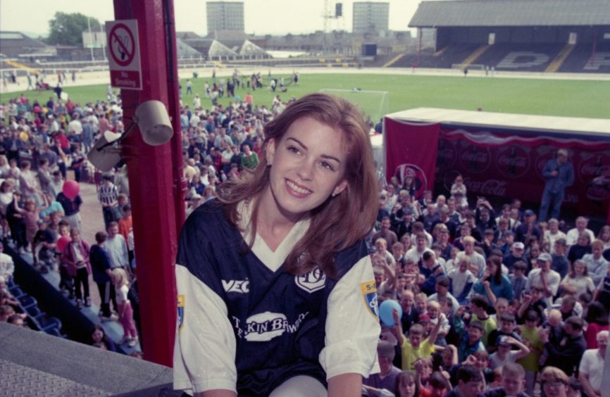 Isla Fisher wearing a Dundee FC at Dens Park in 1997. with the crowd gathered below