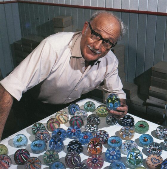 PaulYsart leaning over table covered in glass paperweights