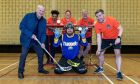 Perth MP Pete Wishart holding floorball stick in goalmouth with group of Perth Parrots players